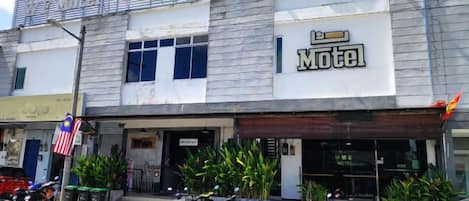 A two-story motel with a signboard, a covered entrance, and several motorcycles parked outside.