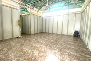 Um quarto com teto alto, vigas de metal e piso de mármore marrom.