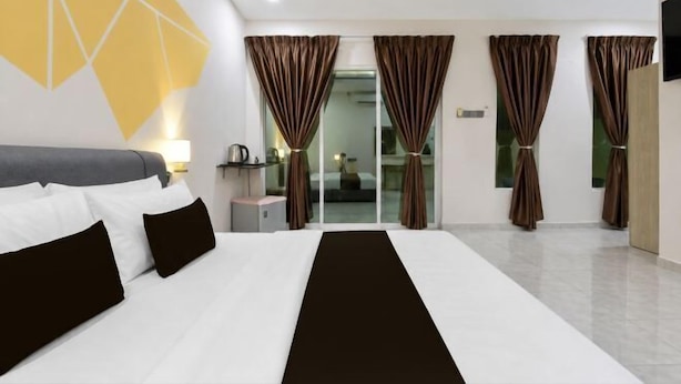 A hotel room with a large bed, a desk with a lamp, and a view of the outside through a glass door. - Collection O Langkawi near pantai cenang formerly tokman inn (Langkawi)