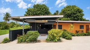 A building with a covered entrance, a pathway leading to the door, and a small outdoor seating area. - Collection O Langkawi near pantai cenang formerly tokman inn (Langkawi)