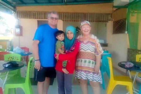 A family of four in a casual dining area with green and yellow plastic chairs and tables. - Collection O Langkawi near pantai cenang formerly tokman inn (Langkawi)