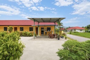 A yellow building with a red roof, a covered patio area, and a paved entrance. - Collection O Langkawi near pantai cenang formerly tokman inn (Langkawi)