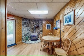 A cozy room with a stone wall, wooden paneling, a fireplace, and a dining table with chairs.