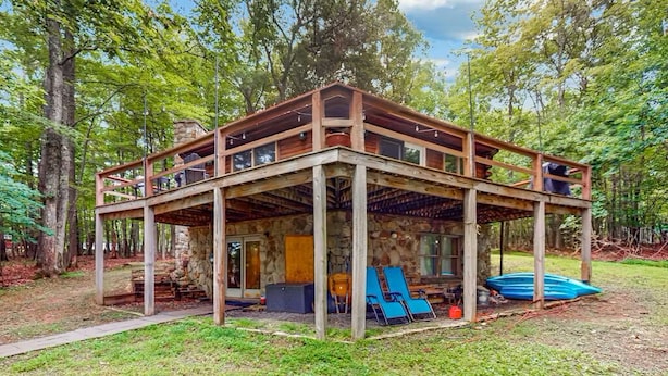 A wooden cabin with a stone foundation, a covered porch, and a small deck area.