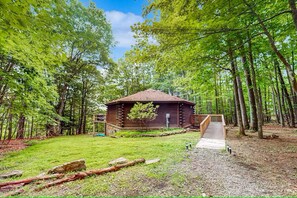 A rustic cabin with a wooden deck and a small ramp leading to the entrance.