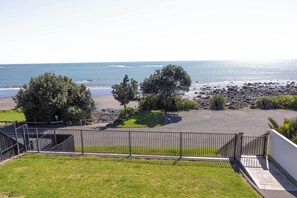 A coastal property with a paved driveway, a fenced area, and a view of the ocean.