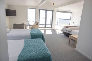 A hotel room with two beds, a small table, a chair, and a balcony with a view. - Beachfront Luxury Retreat & Sauna with Sea Views (New Plymouth)
