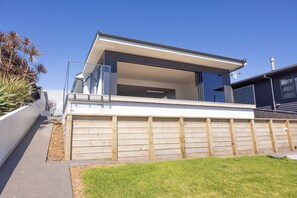 A modern two-story house with a large garage, a balcony, and a clear sky.