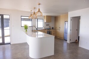 A modern kitchen with a central island, wooden cabinets, and pendant lighting.