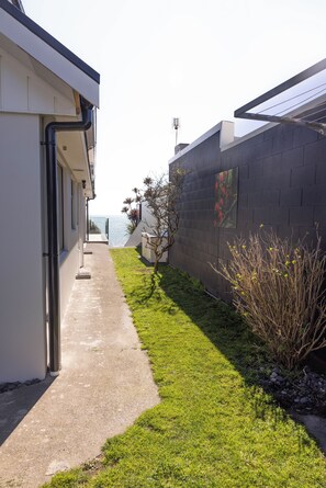 A narrow pathway leading to a building with a view of the sea. - Beachfront Luxury Retreat & Sauna with Sea Views (New Plymouth)