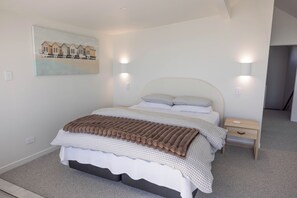 A bedroom with a bed, a bedside table, a nightstand, a wall-mounted light, and a painting on the wall.