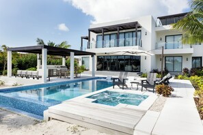 A modern two-story house with a swimming pool, outdoor seating, and a covered patio area.