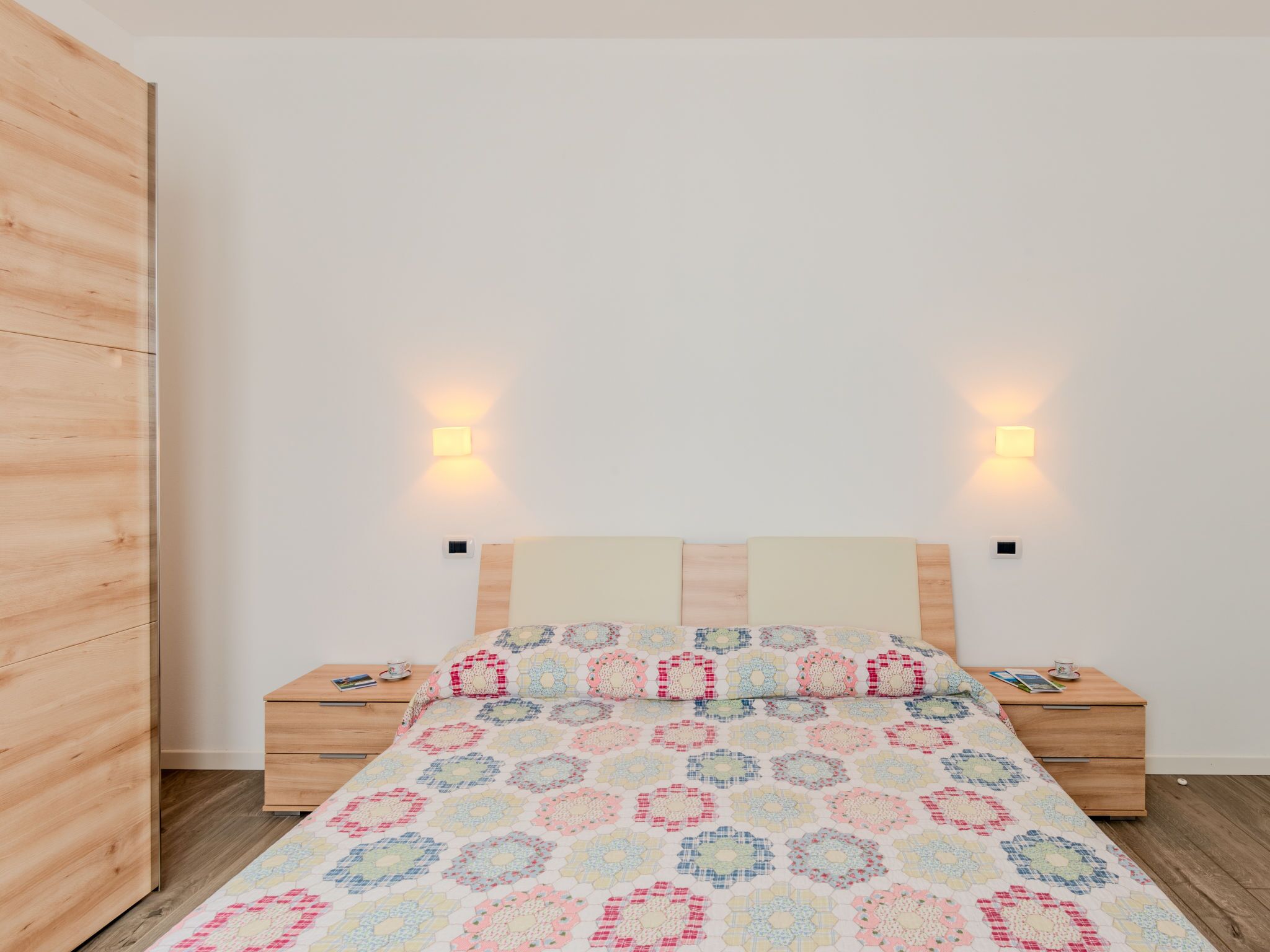 Ein Schlafzimmer mit einem Bett, zwei Nachttischen, einem Nachtschrank und einem Holzschrank.