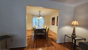 A dining area with a wooden table and chairs, a chandelier, and artwork on the walls. - Spacious and Family Friendly 6-bedrooms house in delightful Silver Spring. (Silver Spring)