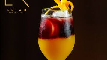 A cocktail in a stemmed glass with a layered drink, ice, and a citrus garnish.