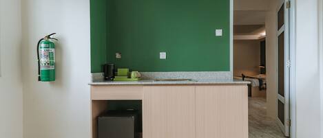 A kitchen with a green wall, a built-in sink, and a fire extinguisher mounted on the wall.