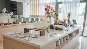 Una cocina moderna con una isla grande, equipada con diversos electrodomésticos y utensilios, y vistas al exterior a través de amplios ventanales.
