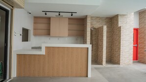 Una cocina moderna con armarios de madera, encimera blanca y una puerta roja al fondo.