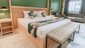 Una habitación de hotel moderna con una cama grande, un banco, un sofá y una mesita.