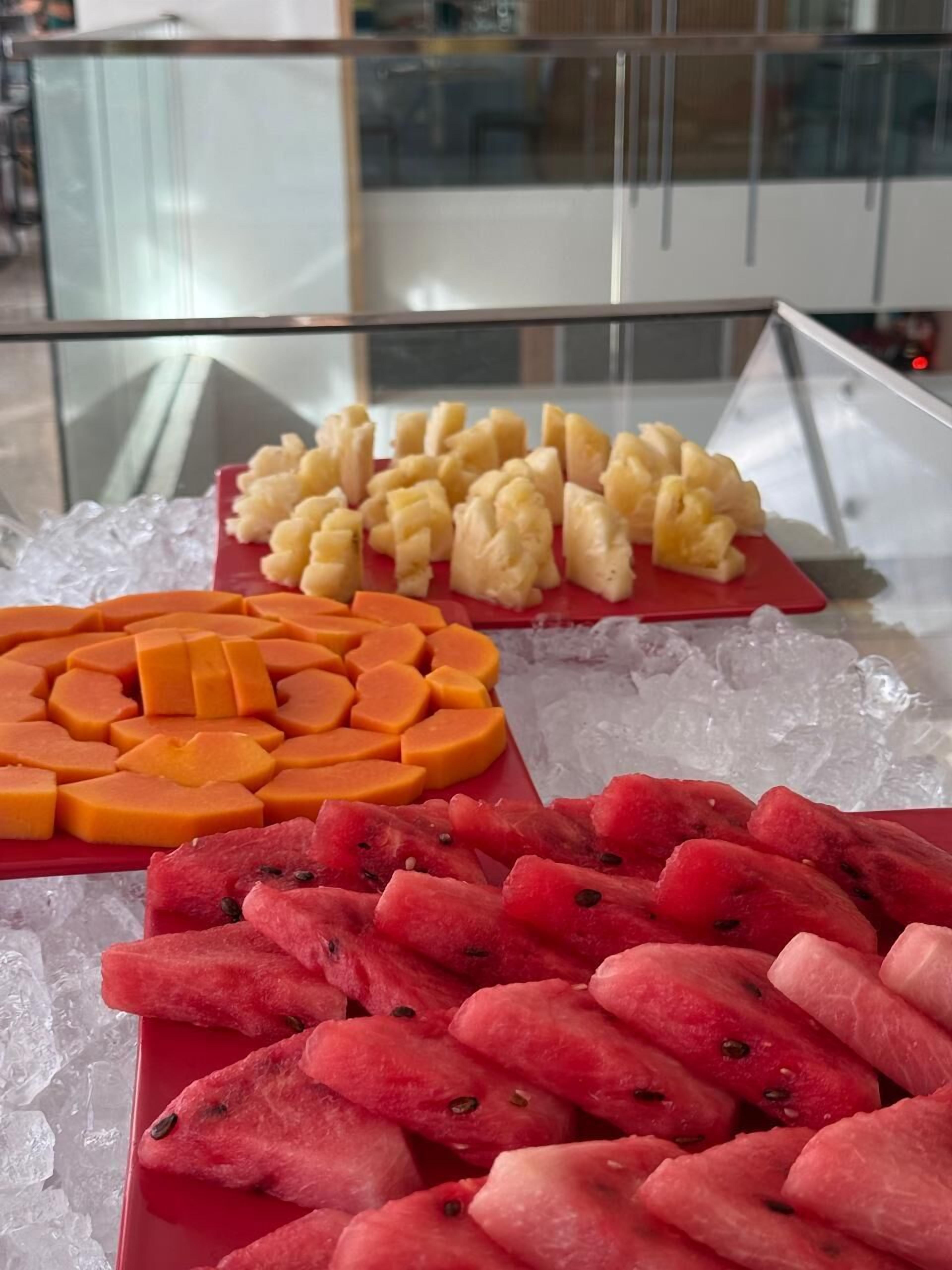 Una exhibición de frutas sobre una mesa de vidrio con hielo.
