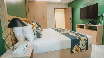 A neatly arranged hotel room with a bed, bedside table, lamp, and a small desk with a telephone.
