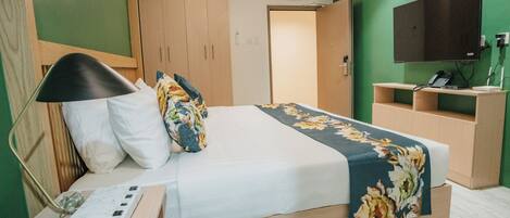 A neatly arranged hotel room with a bed, bedside table, lamp, and a small desk with a telephone.