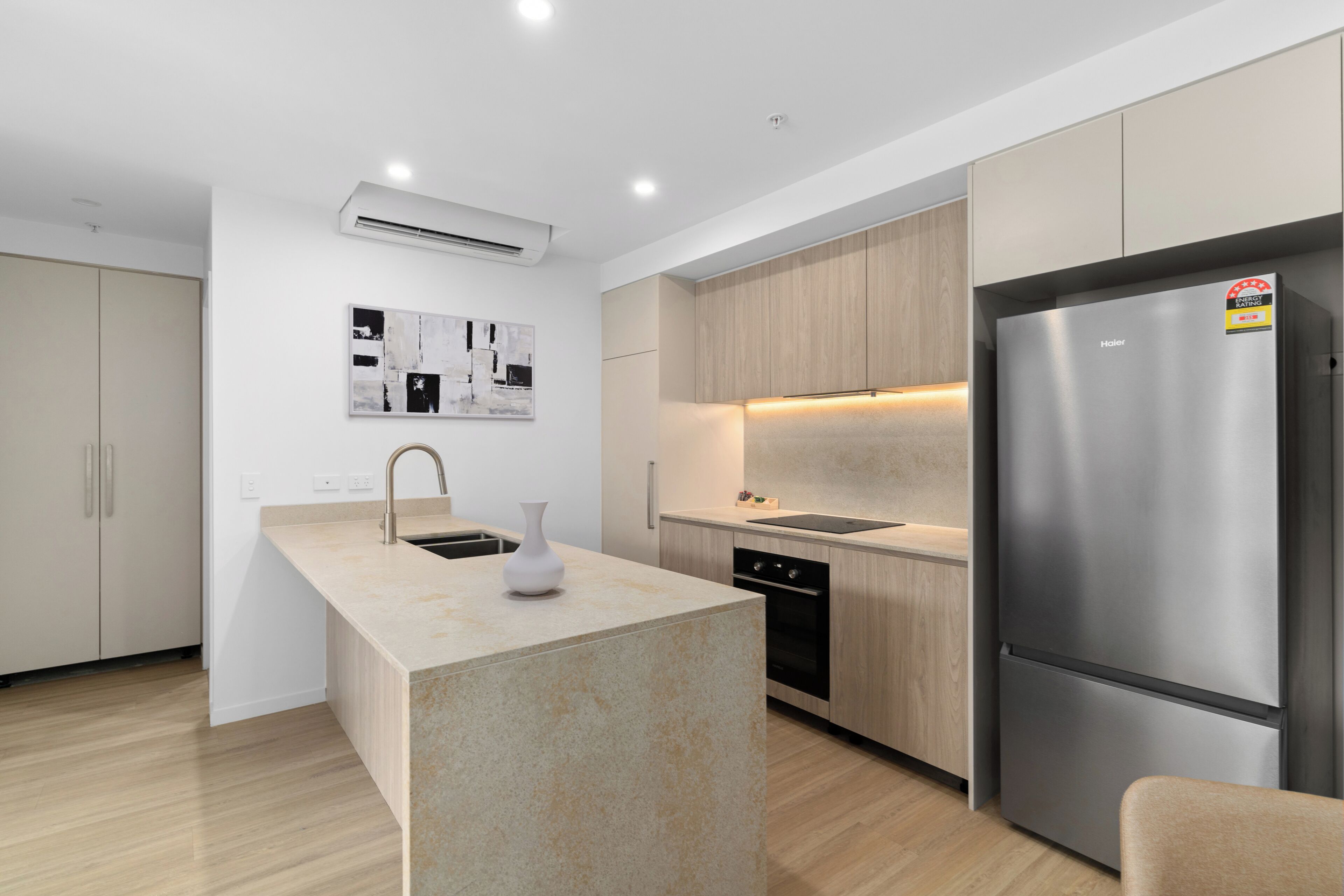 A modern kitchen with a central island, stainless steel appliances, and wooden cabinetry.