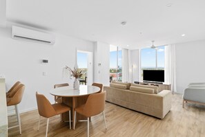 A modern living room with a sofa, TV, and dining area with chairs and a table.