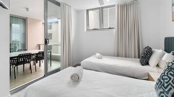 Une chambre d’hôtel avec deux lits, un ventilateur de plafond, une fenêtre avec des rideaux et une vue sur un espace repas.
