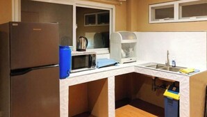 Une cuisine compacte équipée d’un réfrigérateur, d’un four à micro-ondes, d’une machine à café et d’un évier.