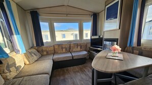 Un intérieur de camping-car accueillant, avec un canapé d’angle, une table à manger et un téléviseur.