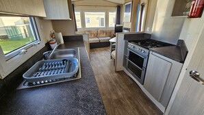 Une cuisine compacte équipée d’une cuisinière, d’un four et d’un évier. Une fenêtre laisse entrer la lumière naturelle et offre une vue sur l’extérieur.