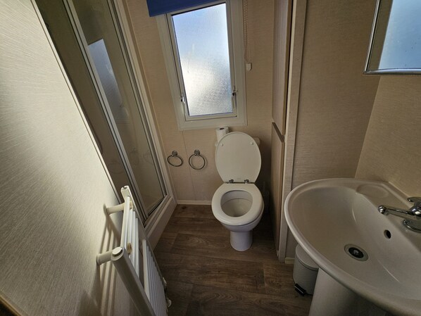 A small bathroom with a toilet, a sink, and a window.