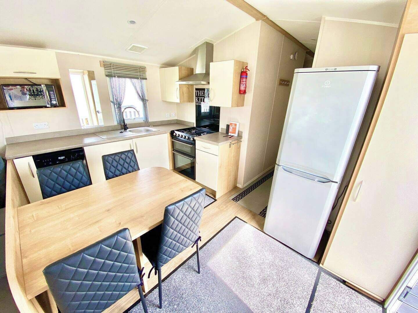 A compact kitchen with a dining area, including a stove, oven, sink, and a refrigerator.