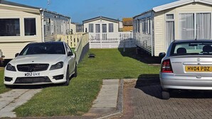 A caravan park with two caravans, one white and one silver, parked on a paved area with grass in between. - Luxury Chichester caravan  Seaside Retreat (Chichester)