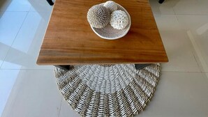Ein modernes Wohnzimmer mit einem grauen Sofa, zwei passenden Zierkissen, einem Holztisch und zwei gewebten Poufs.