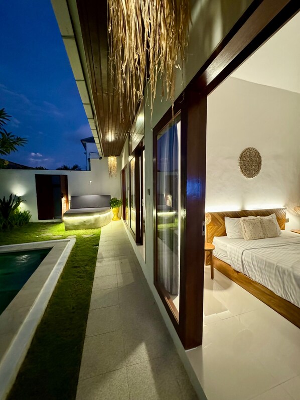 A modern bedroom with a large bed, a small bedside table, and a wall-mounted circular decoration.