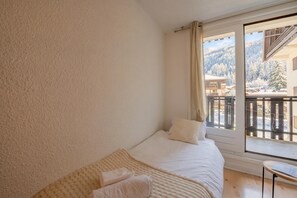 A bedroom with a bed, a window, and a view of a snowy landscape.