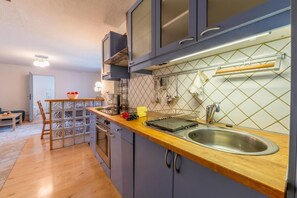 Una cocina moderna con encimera de madera, pileta de acero inoxidable y horno empotrado.