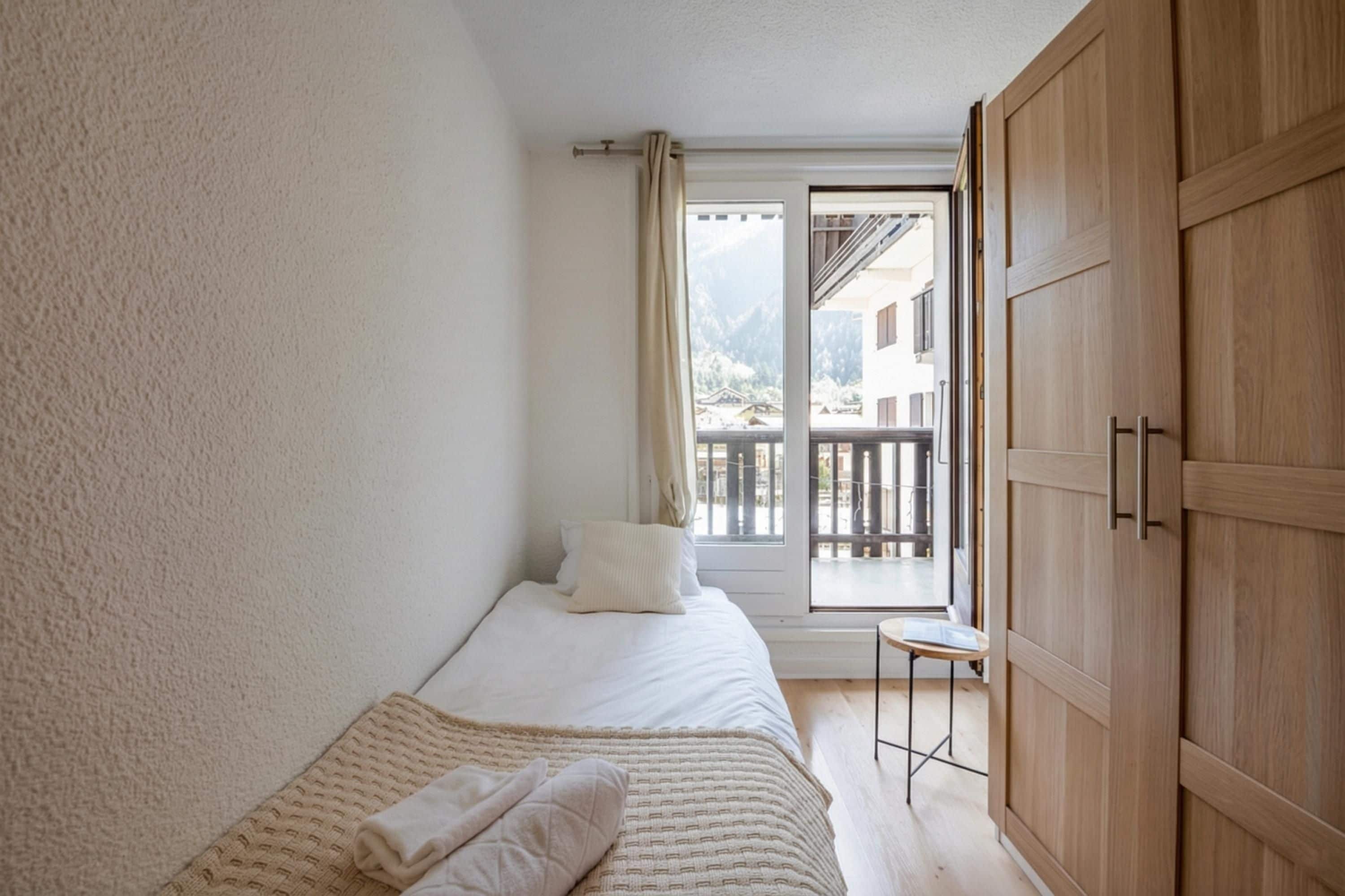 A bedroom with a bed, a small table, and a wardrobe.
