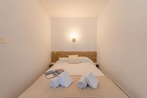 Una habitación de hotel con una cama, una mesita de noche, una lámpara y toallas sobre la cama.