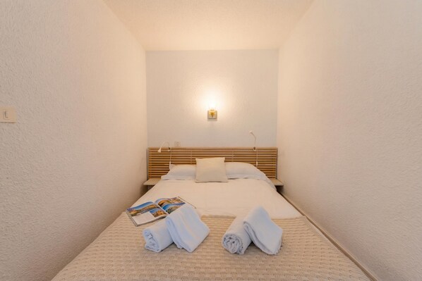 Een hotelkamer met een bed, nachtkastje, lamp en handdoeken op het bed.