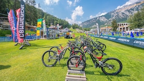 Een mountainbike evenement met meerdere fietsen geparkeerd op een grasveld, omringd door tenten en vlaggen.