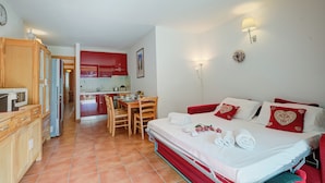 Een slaapkamer met een bed, bureau en een kitchenette.