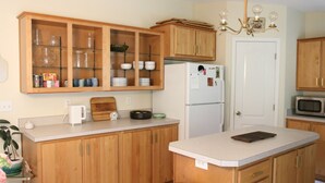 Une cuisine avec des meubles de rangement en bois, un réfrigérateur blanc, un four à micro-ondes et une machine à café.