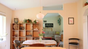 Un coin repas comprenant une table en marbre, des chaises, un vase avec des fleurs et une bibliothèque contenant divers objets.