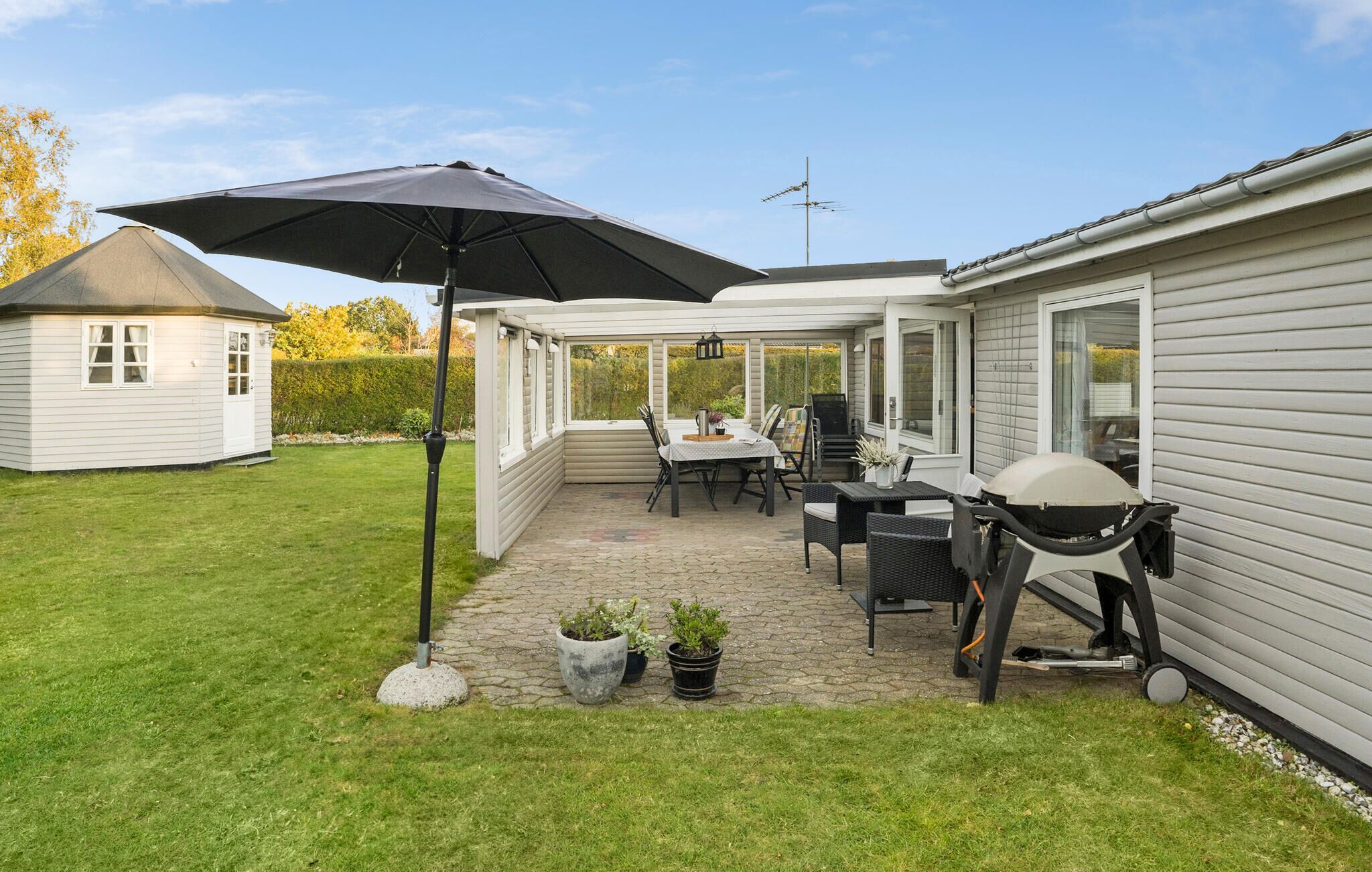 A patio area with a table and chairs, a grill, and a large umbrella.