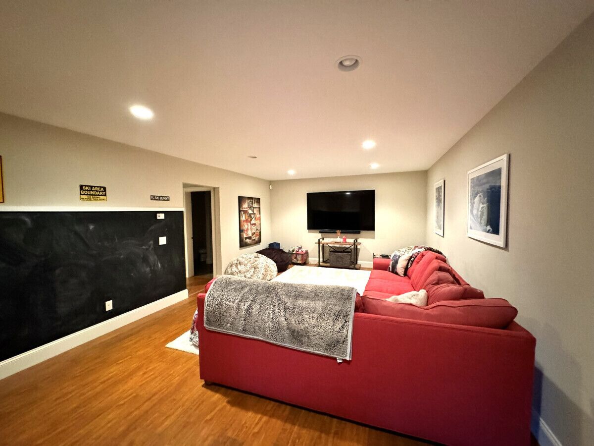 Una sala de estar moderna con un sofá rojo, una chimenea y un televisor de pantalla plana montado en la pared.