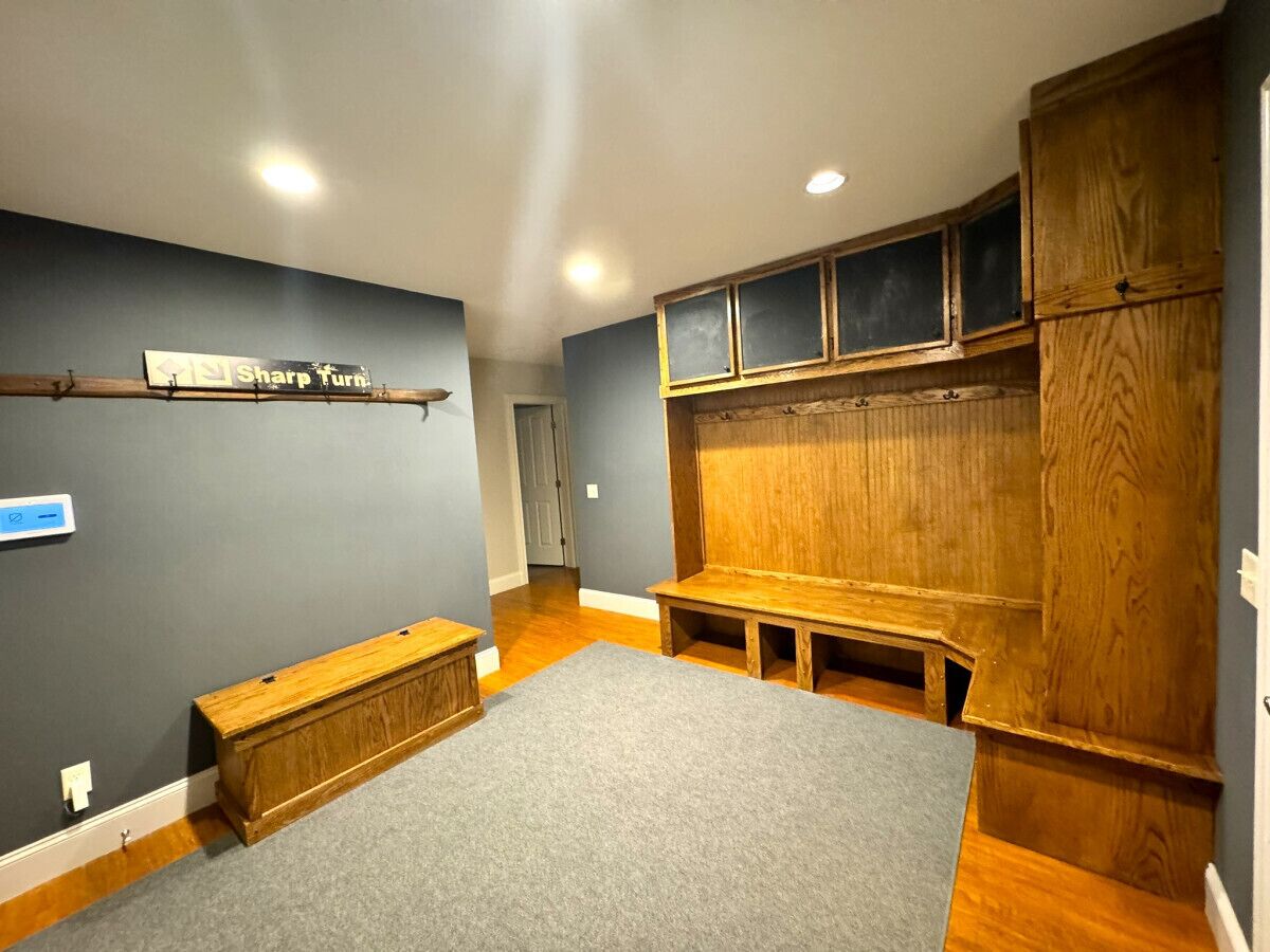A room with a grey carpet, wooden bench, and a bench with a backrest.