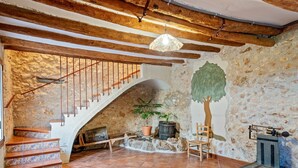 Un intérieur rustique avec un mur en pierre, un escalier en bois, un sol carrelé et un luminaire suspendu.
